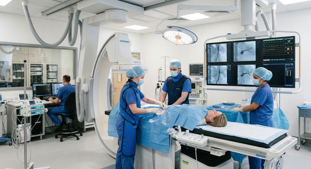 Zespół medyczny wykonuje angiografię nerkową w pracowni zabiegowej, monitorując obraz naczyń na ekranach