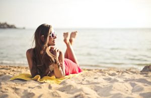 uśmiechnięta kobieta leży na plaży i opala się