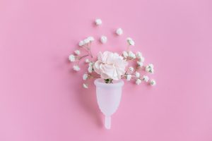 kubeczek menstruacyjny na różowym tle z kwiatami