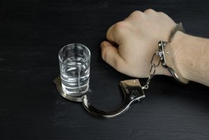 alkoholiik przywiązany łańcuchem do kieliszka z wódką