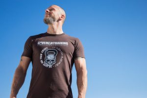 dobrze zbudowany mężczyzna w ciemnej koszulce stojący na tle niebieskiego nieba