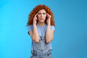 kobieta z migreną trzymająca się za głowę