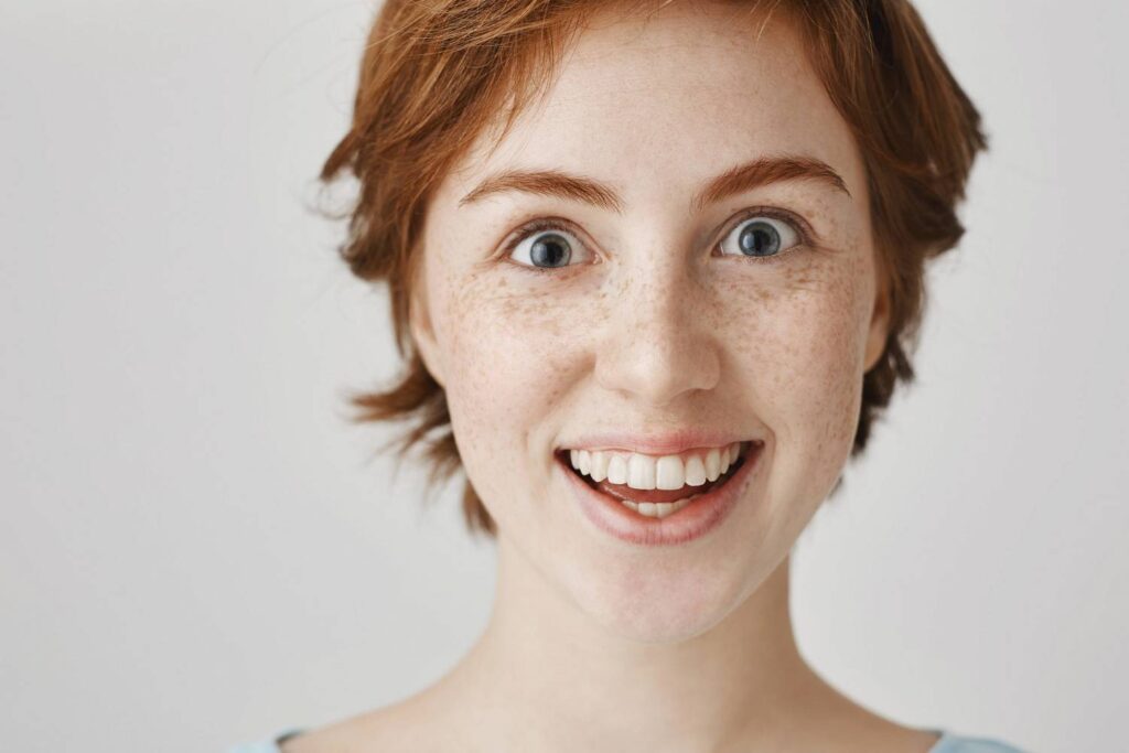 kobieta uśmiechająca się szeroko z widocznymi zębami bez plam i przebarwień