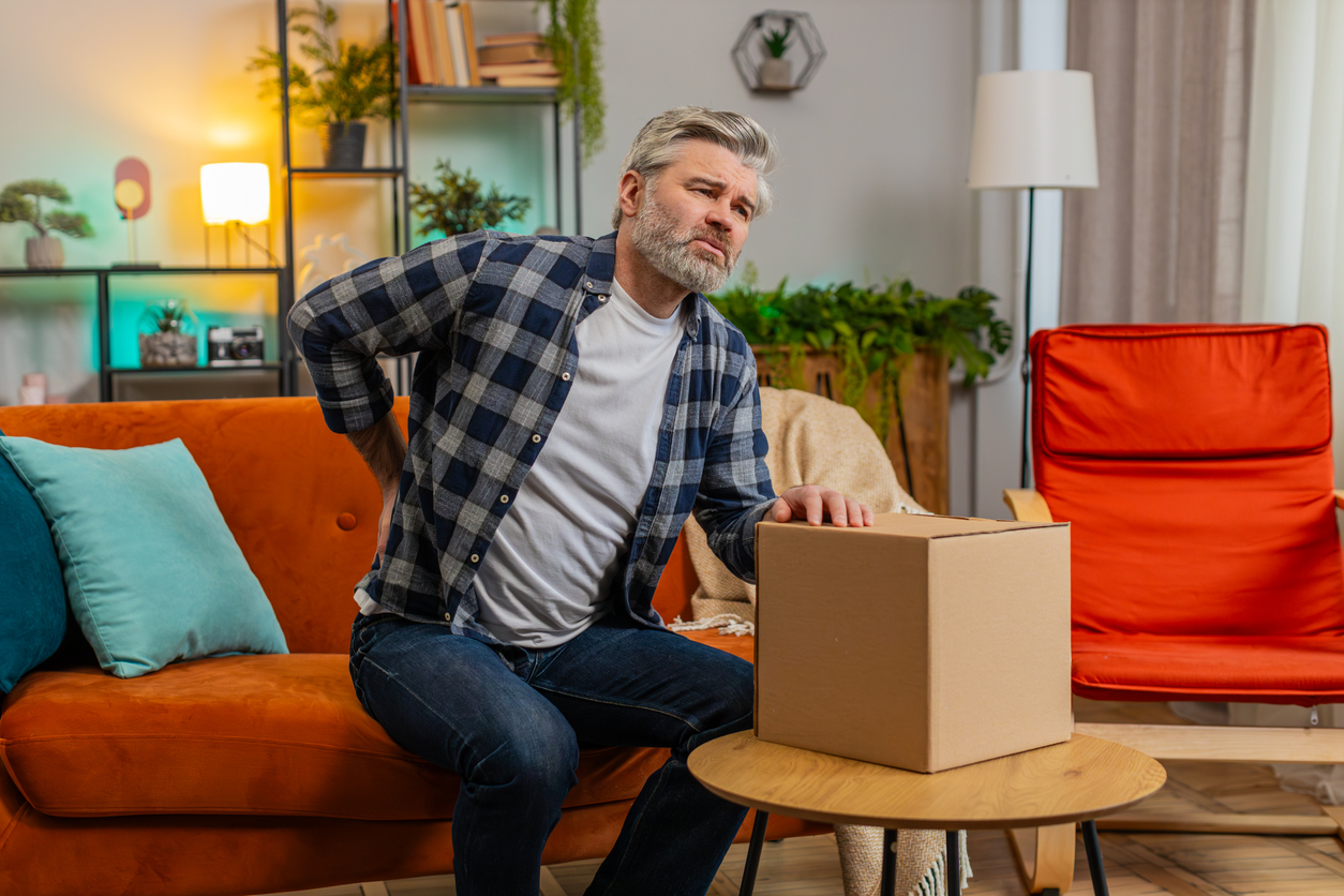 mężczyzna w grymasie twarzy wywołanym bólem trzymający się za lędźwia