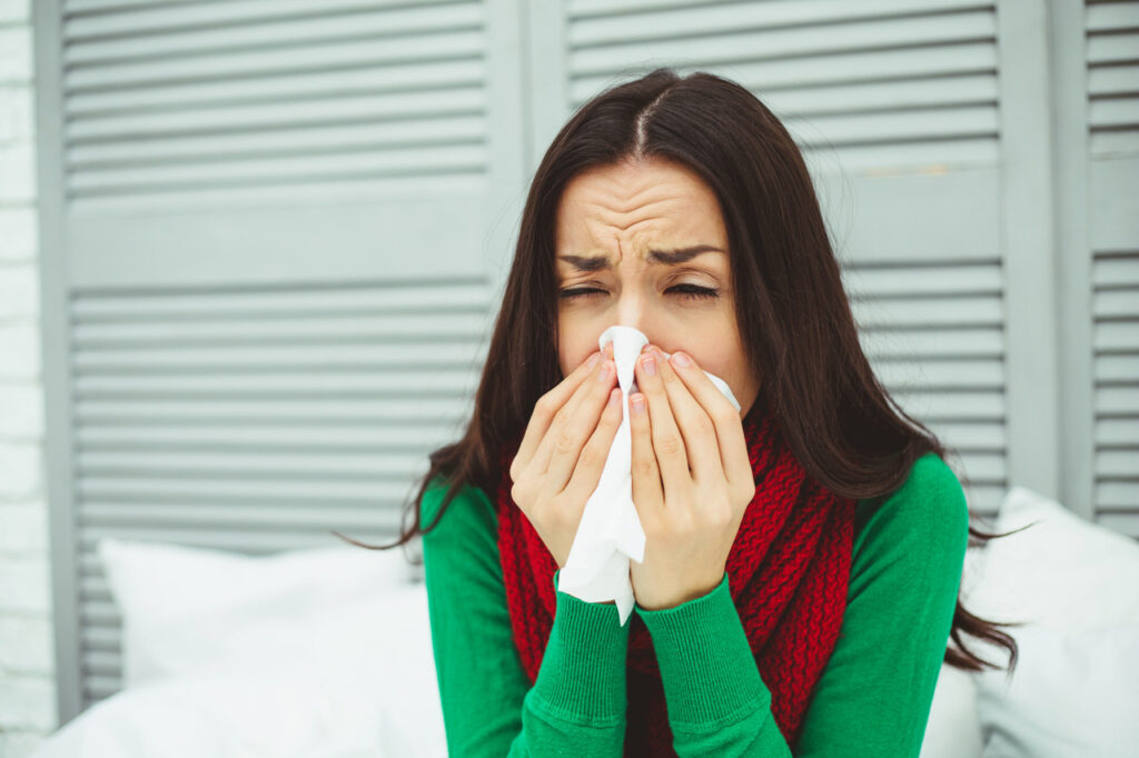kobieta z aktywnym zapaleniem zatok kichająca w chusteczkę
