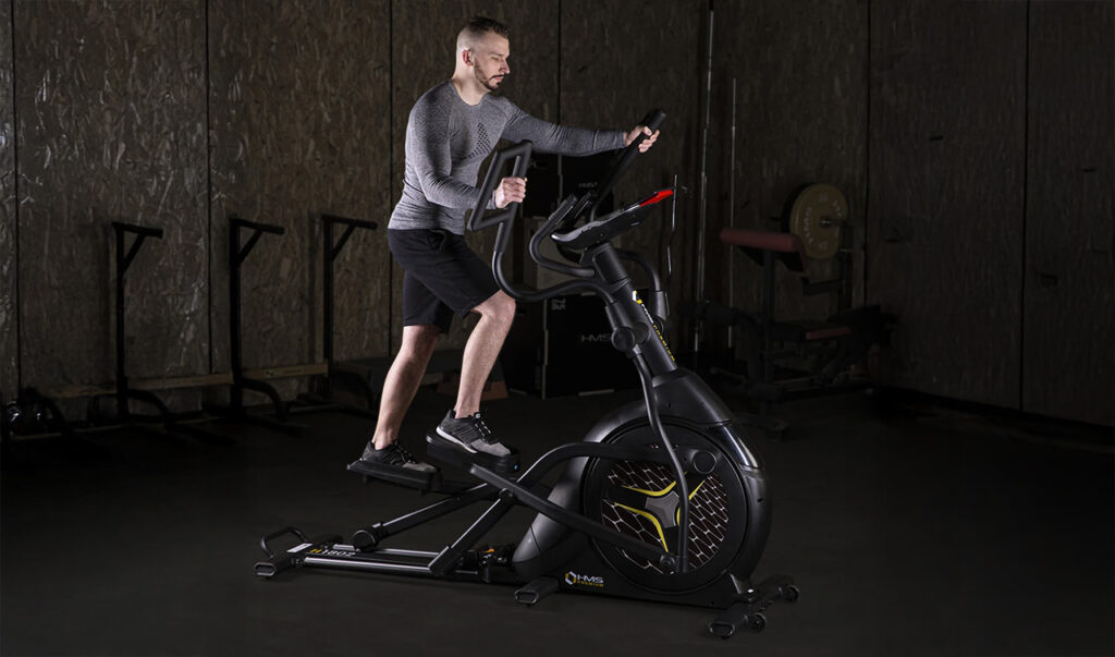 Mężczyzna ćwiczący na orbitreku podczas treningu cardio na siłowni.